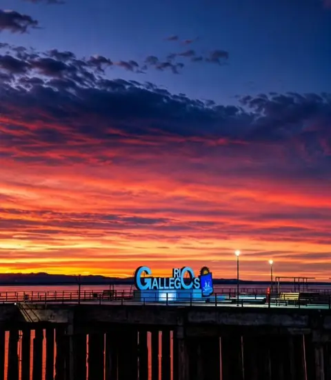 Atardecer sobre la costanera de Río Gallegos, con el cartel de la ciudad iluminado